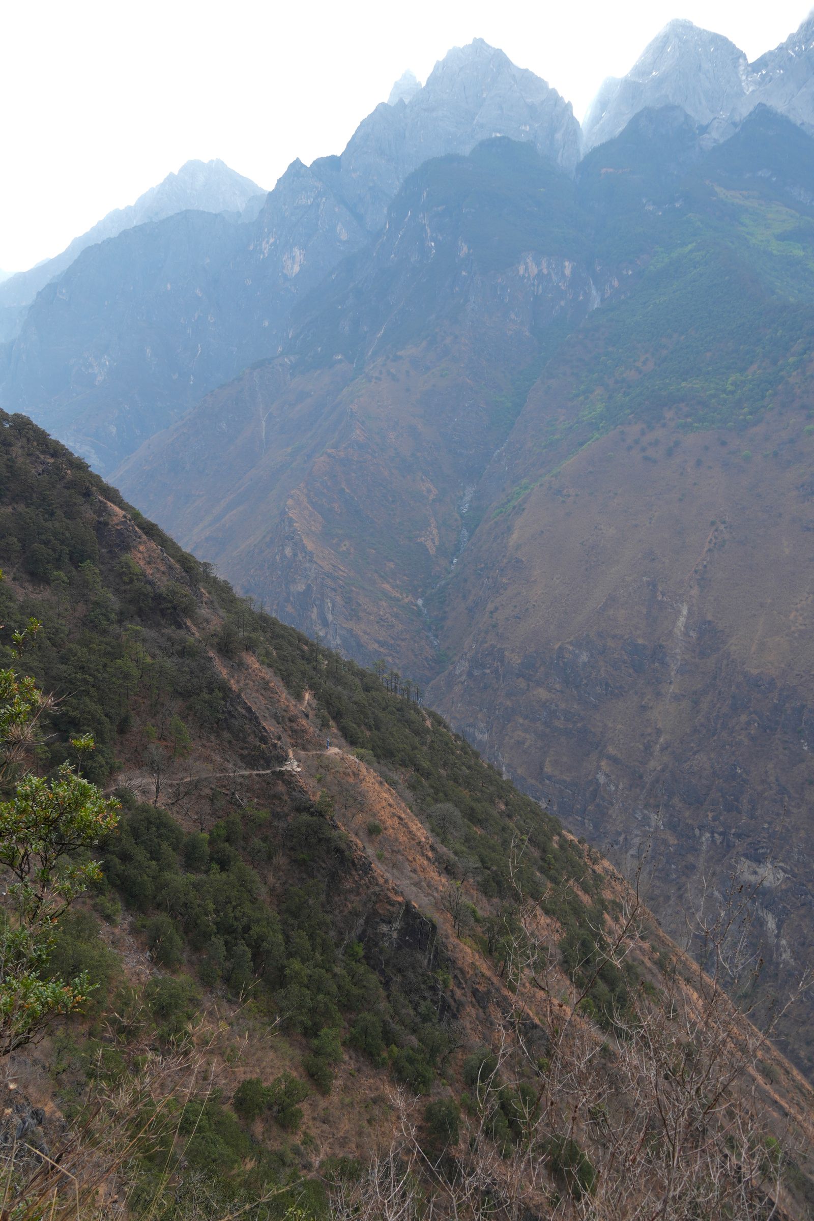 A narrow trail below rocky peaks in Tiger Leaping Gorge