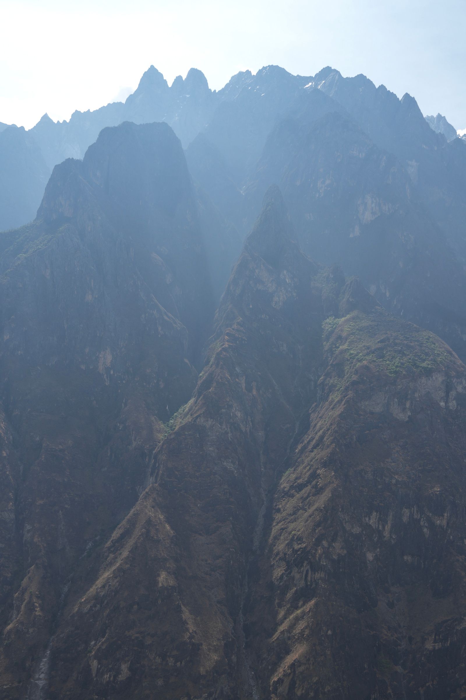 Jagged mountain ridges above steep cliffs in haze, Tiger Leaping Gorge
