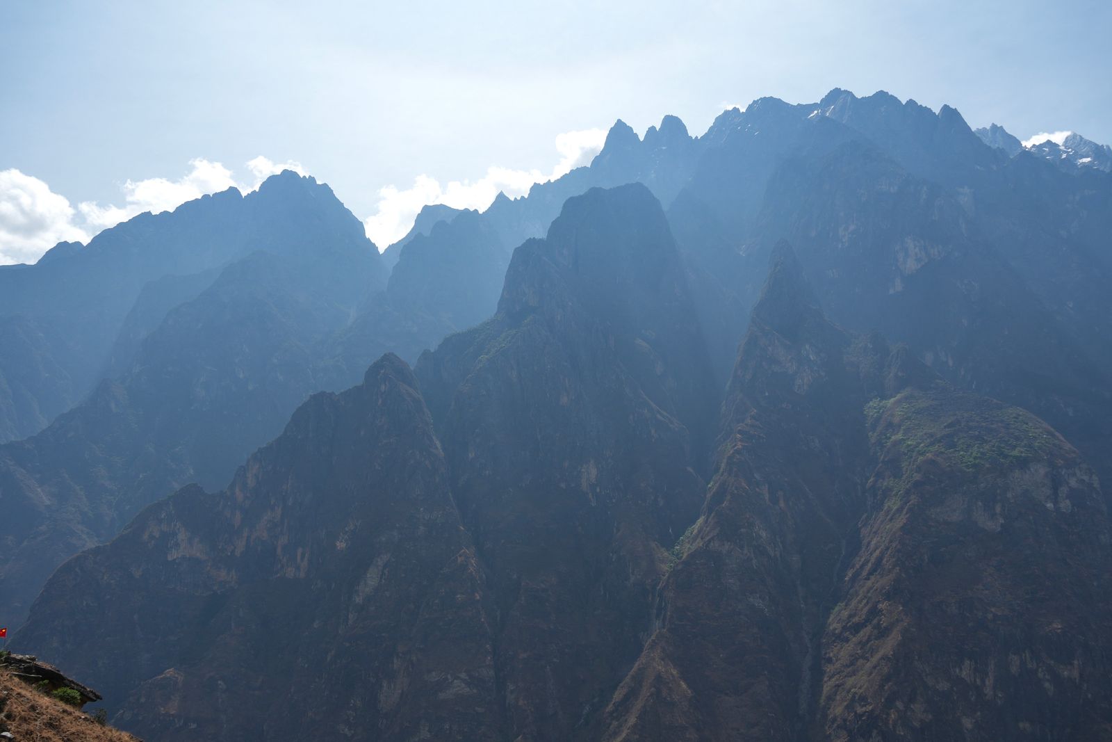 Layered mountain peaks above rocky slopes in hazy backlight, Tiger Leaping Gorge