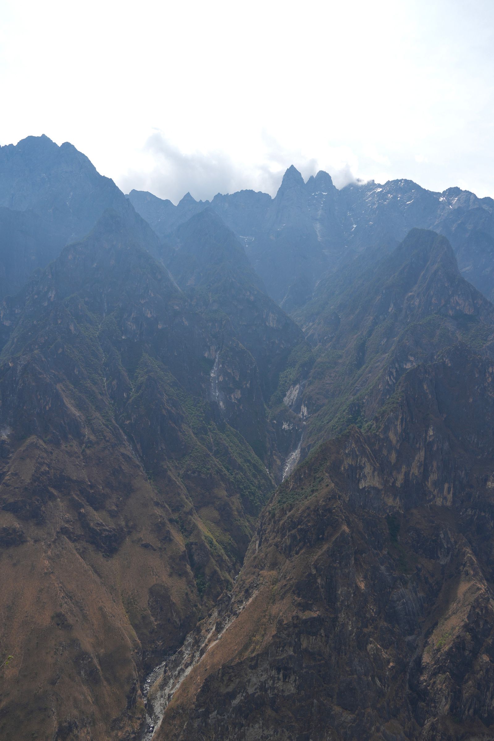 Cloud-covered mountain peaks above a narrow rocky ravine, Tiger Leaping Gorge