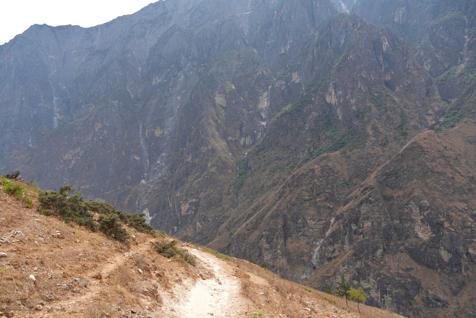 Tiger Leaping Gorge beyond a dirt trail and dry shrubs