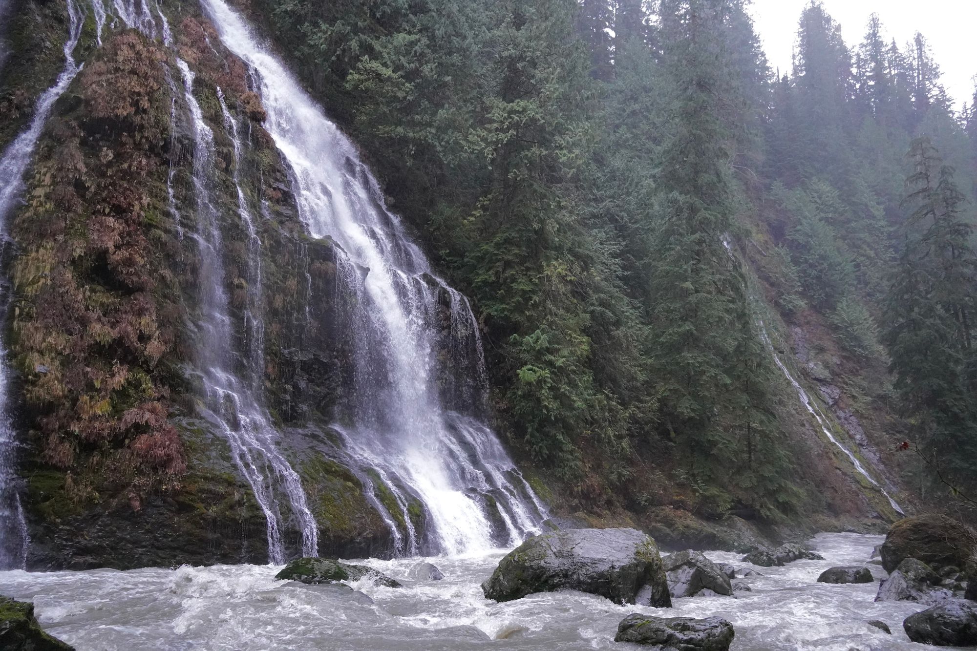 Waterfall fanning down mossy rock into a boulder-filled stream, Cascades