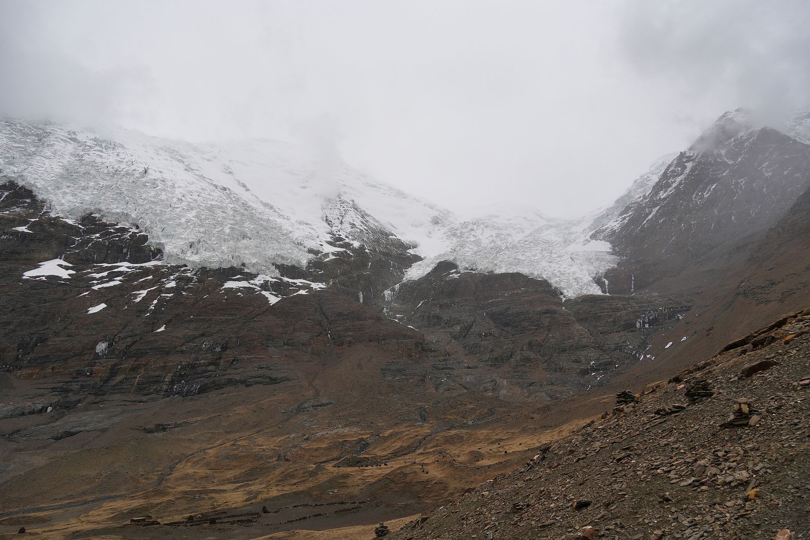 Glaciers above dark cliffs and a rocky valley, Tibetan plateau