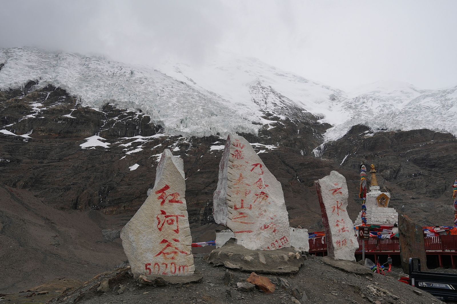 Inscribed stone slabs below an ice-covered rocky slope, Tibetan plateau
