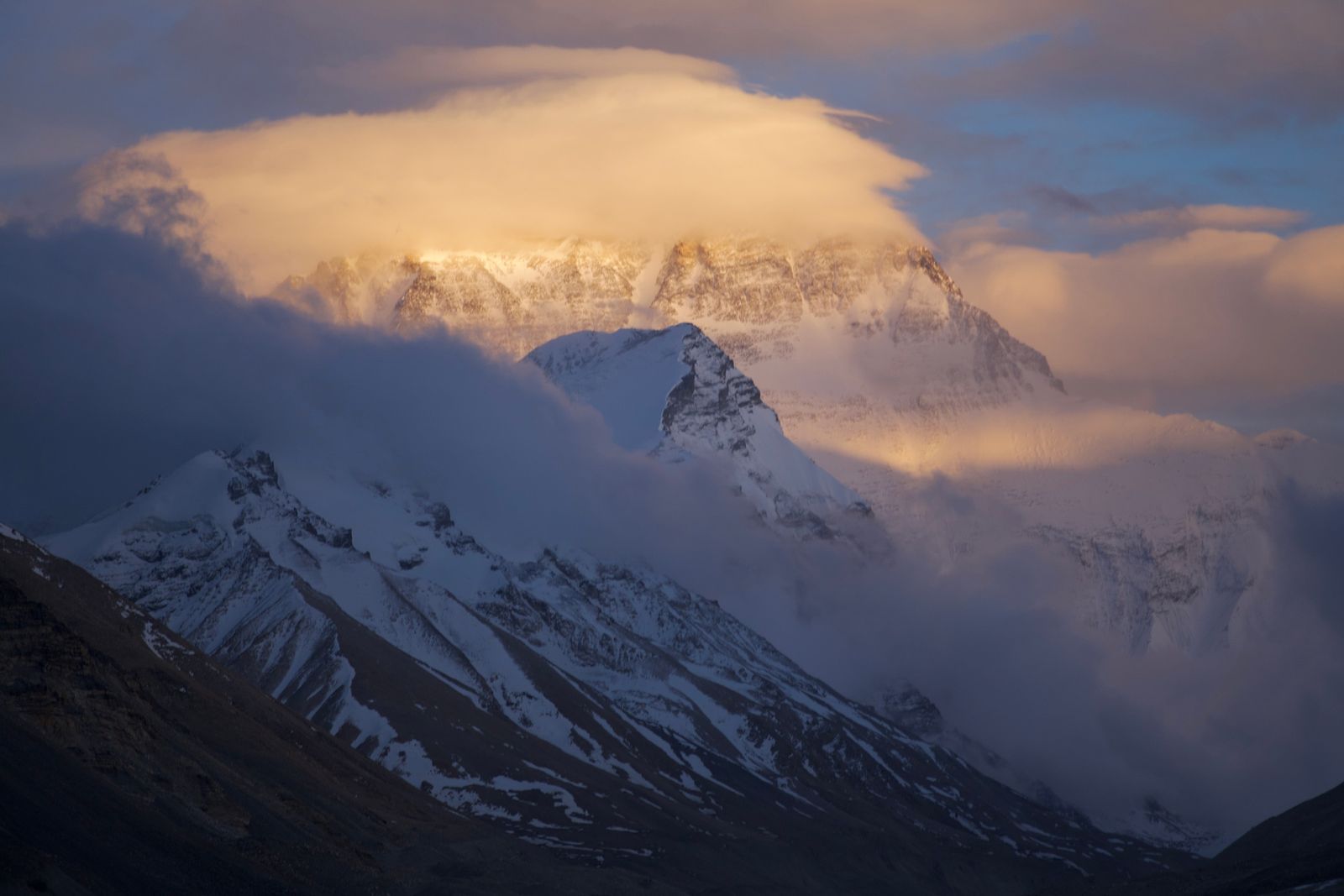 Mount Everest in golden light with clouds covering the summit