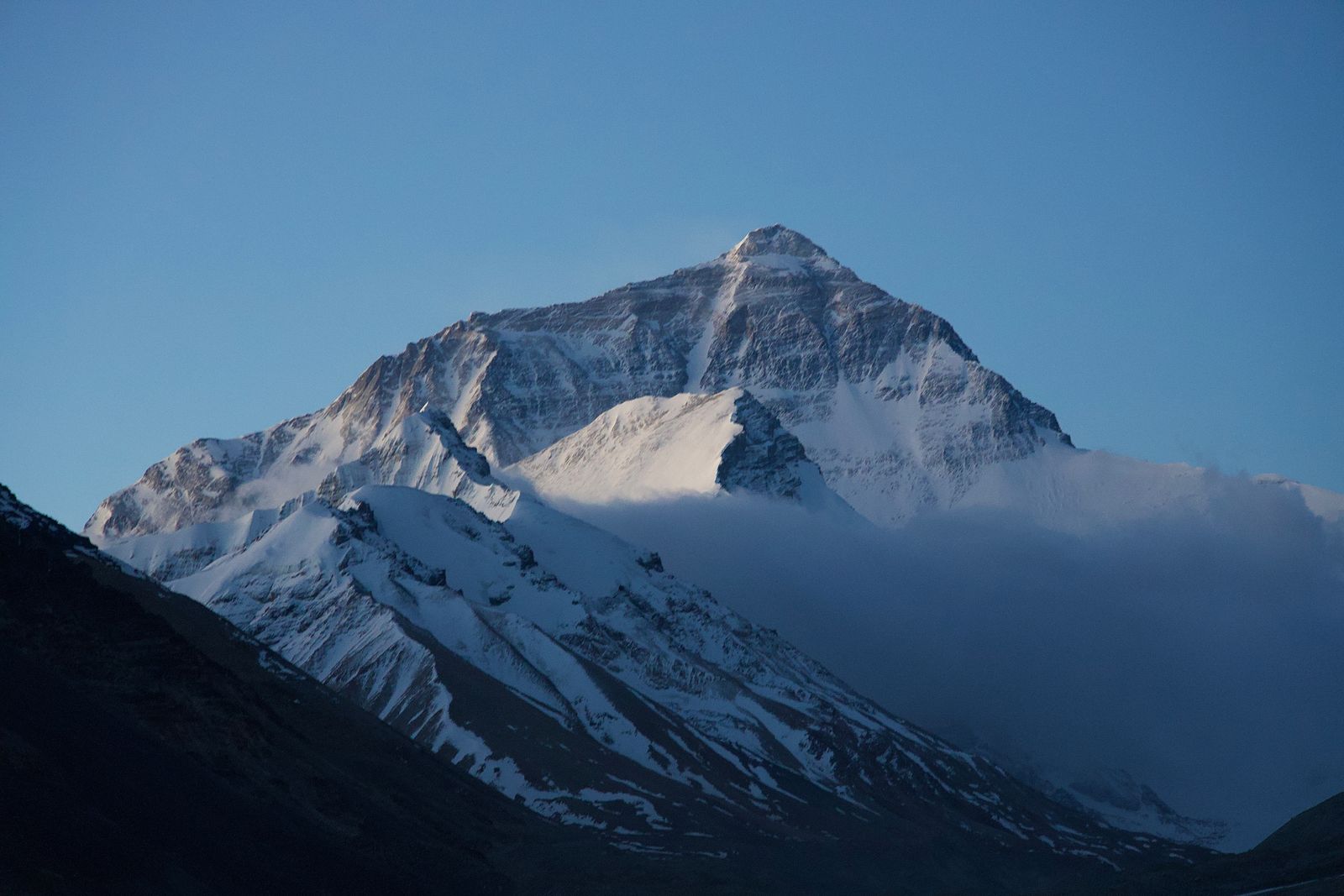 Mount Everest above a cloud bank beneath blue sky