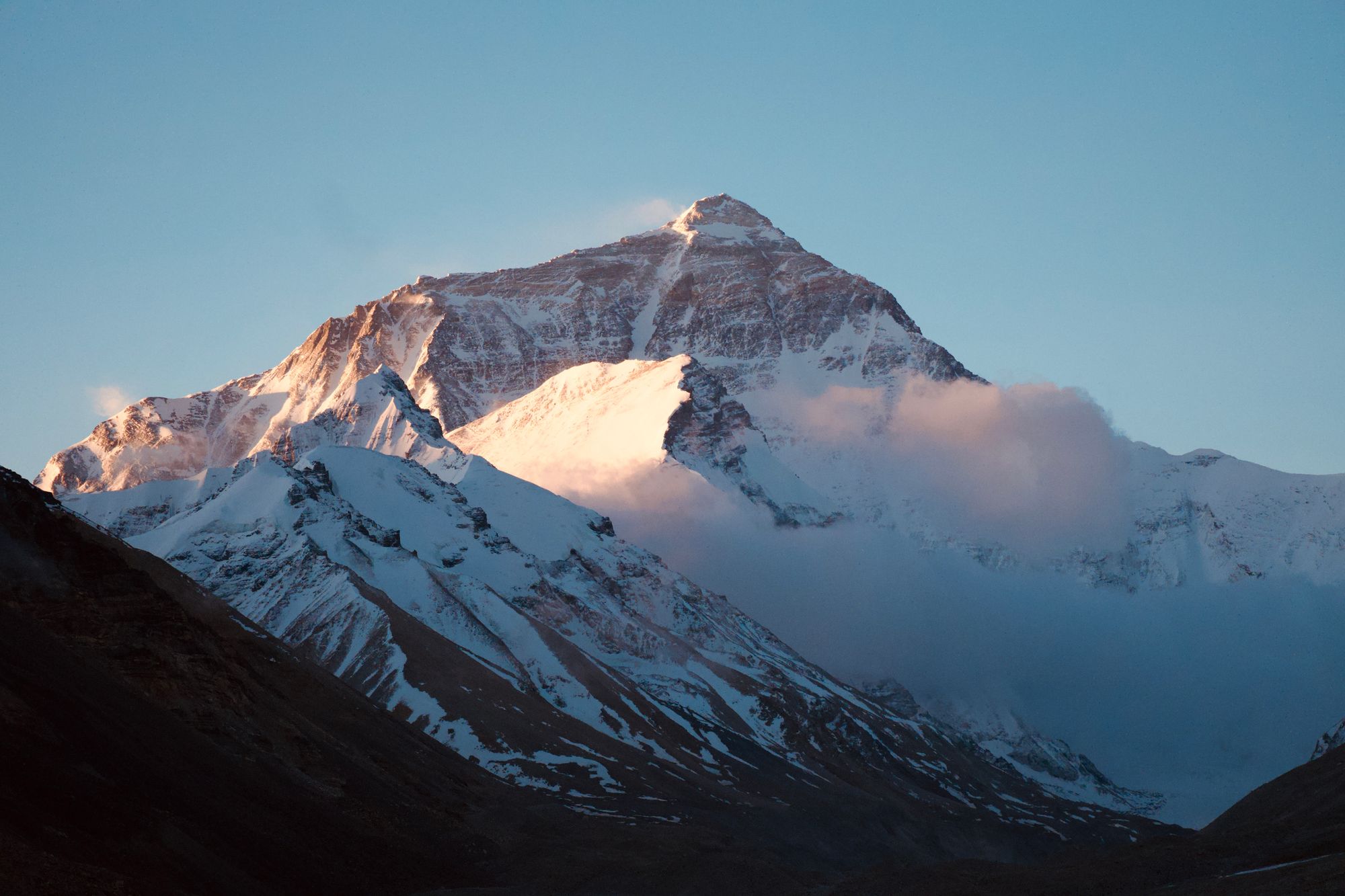 Mount Everest above snowy ridges in warm light