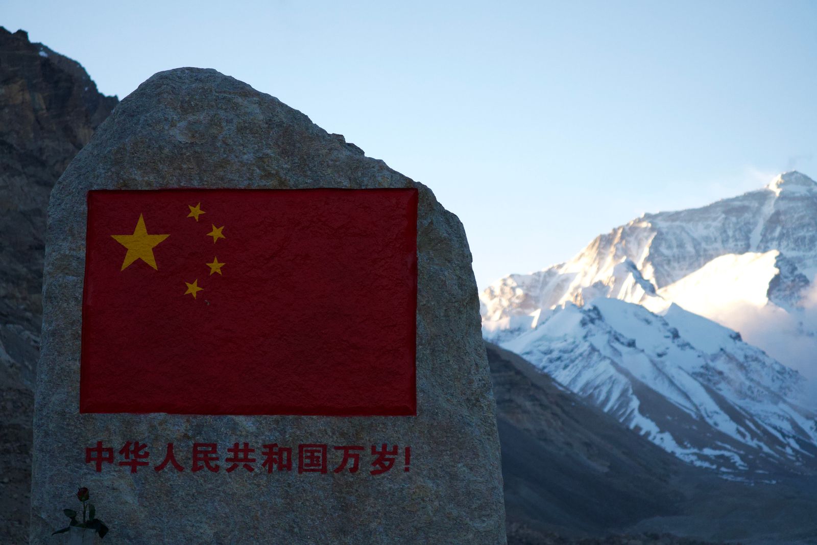 A stone marker with a painted flag below Mount Everest