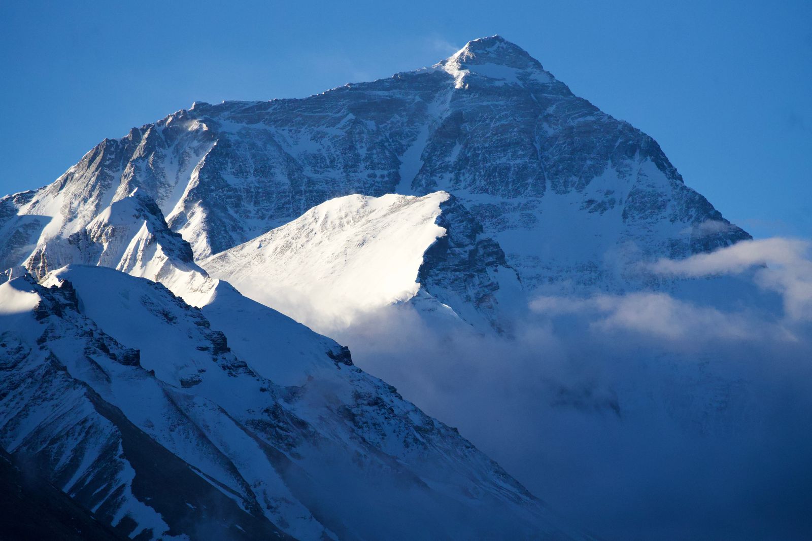 Mount Everest beyond sunlit snowy ridges and low clouds