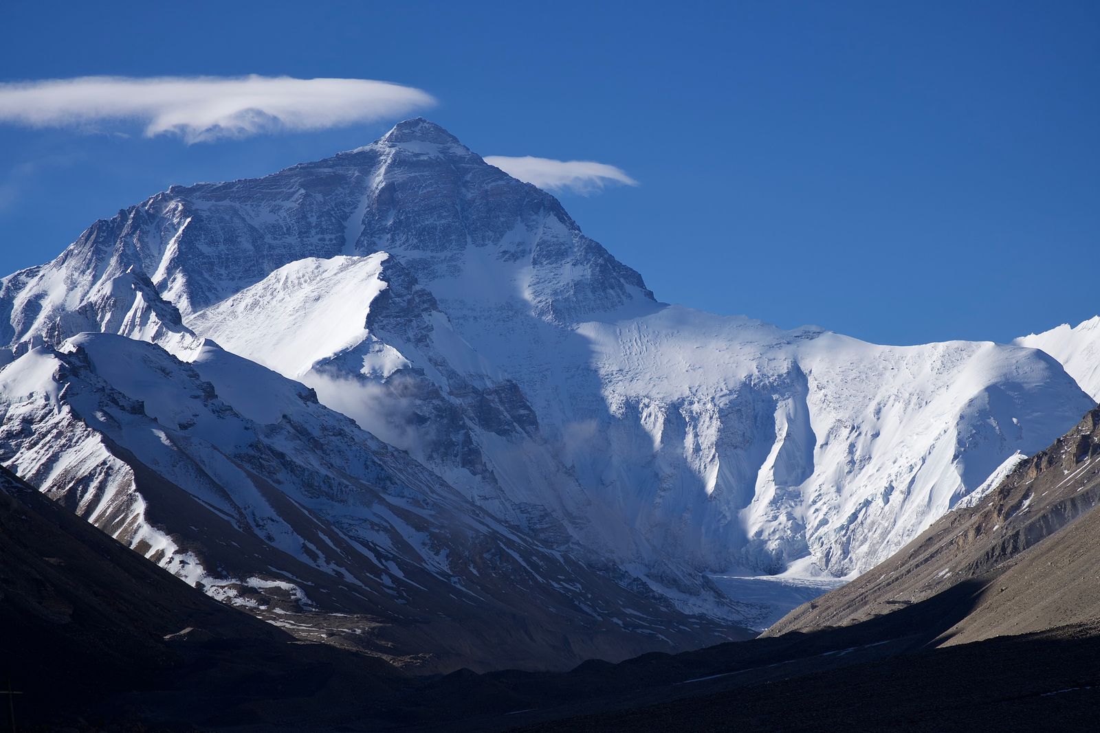 Everest north face above dark rocky slopes