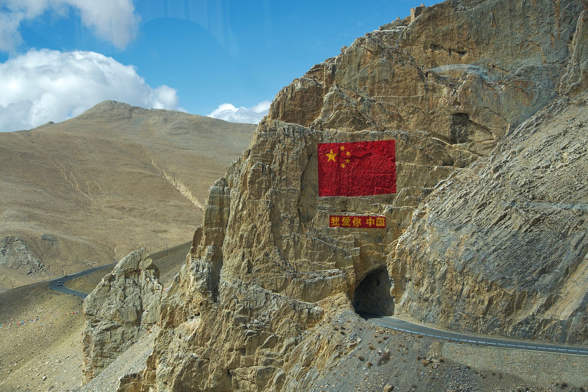 A red flag mural on a cliff above a tunnel, Tibetan plateau