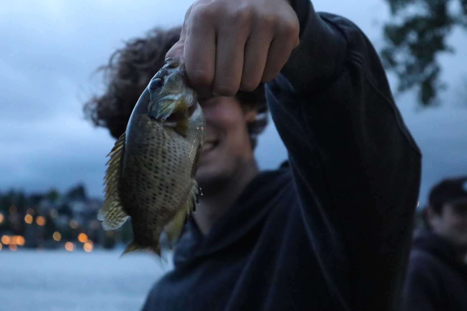 A spotted fish held by hand above water, near Seattle