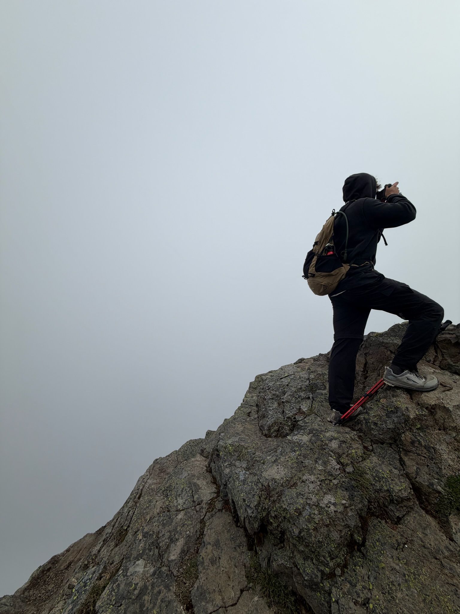 A photographer holding a camera on a ledge in fog, Ball Mountain