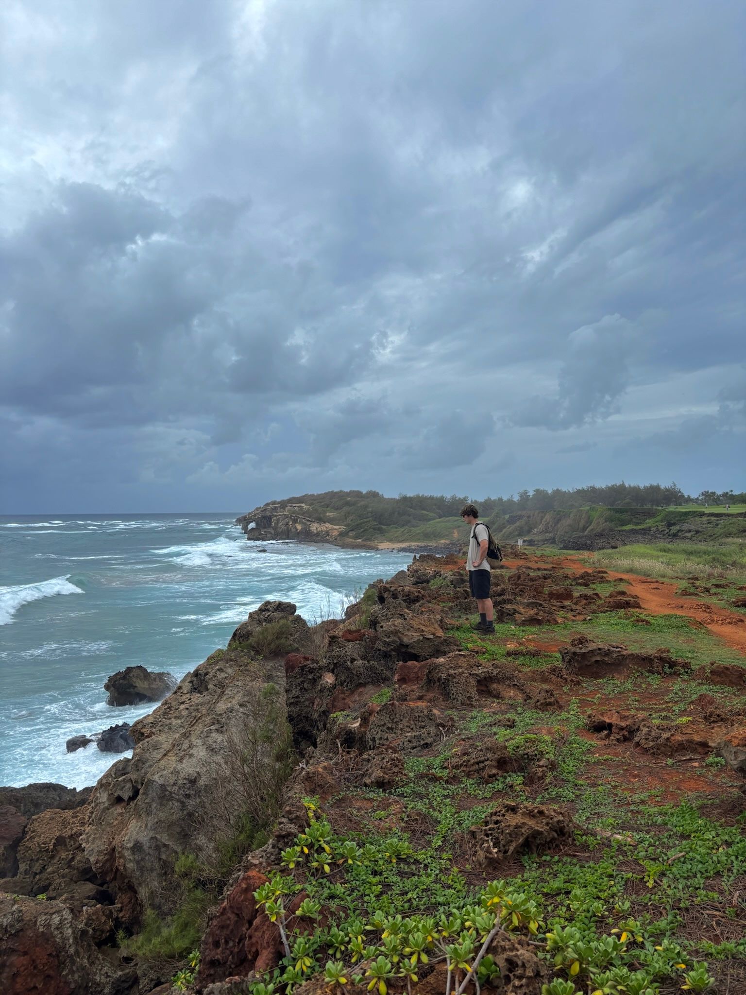 Rocky coast with breaking waves and a backpacker, Napali Coast