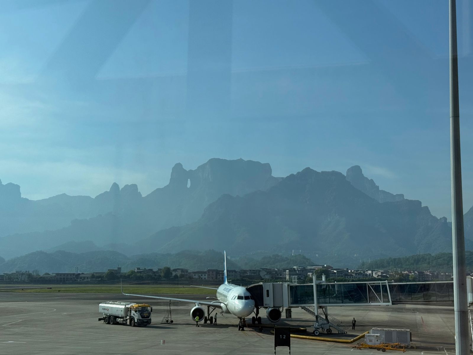 A parked airplane below a hazy mountain ridge, Zhangjiajie