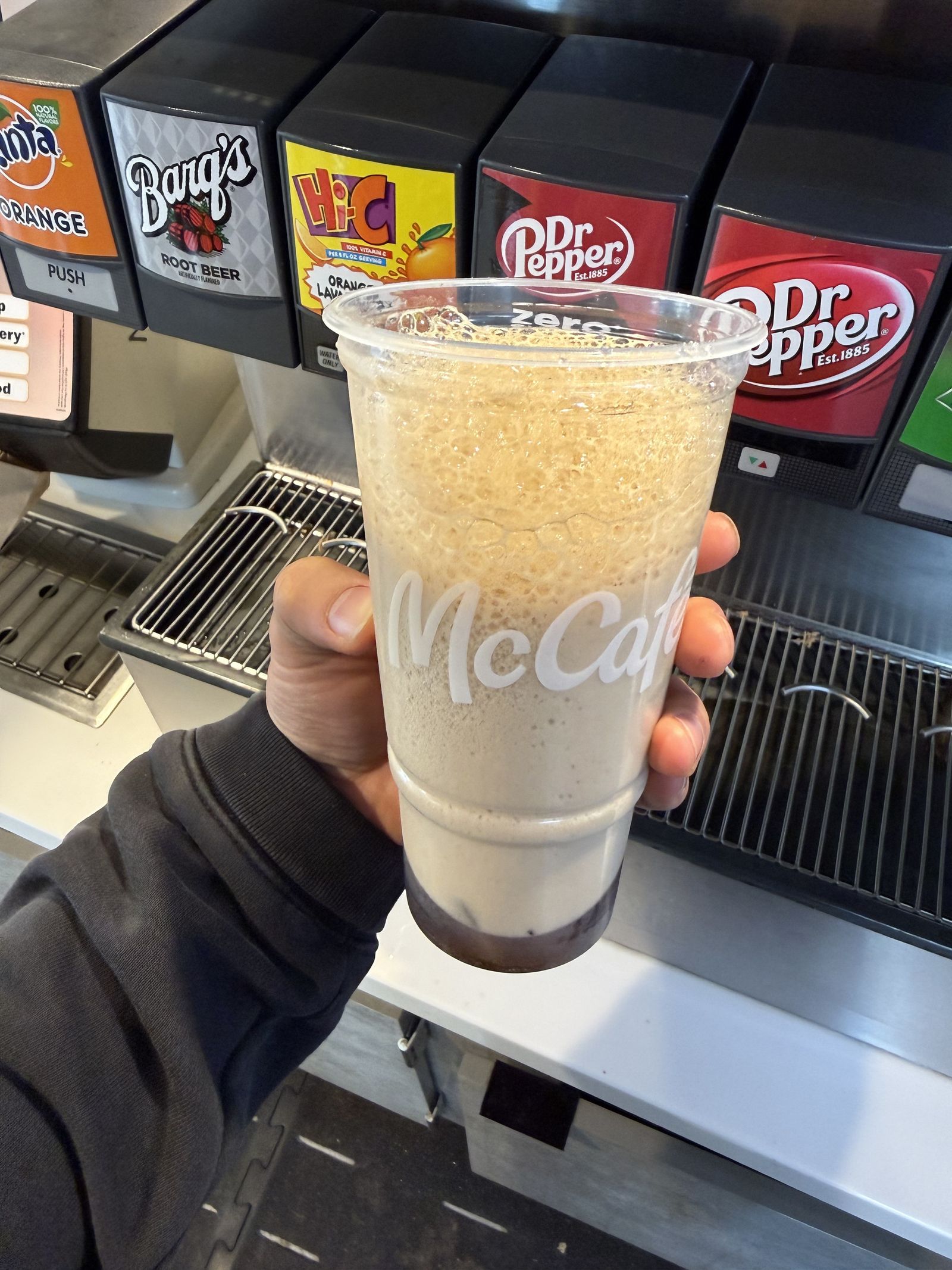 A foamy layered drink held before a soda fountain, Ball Mountain