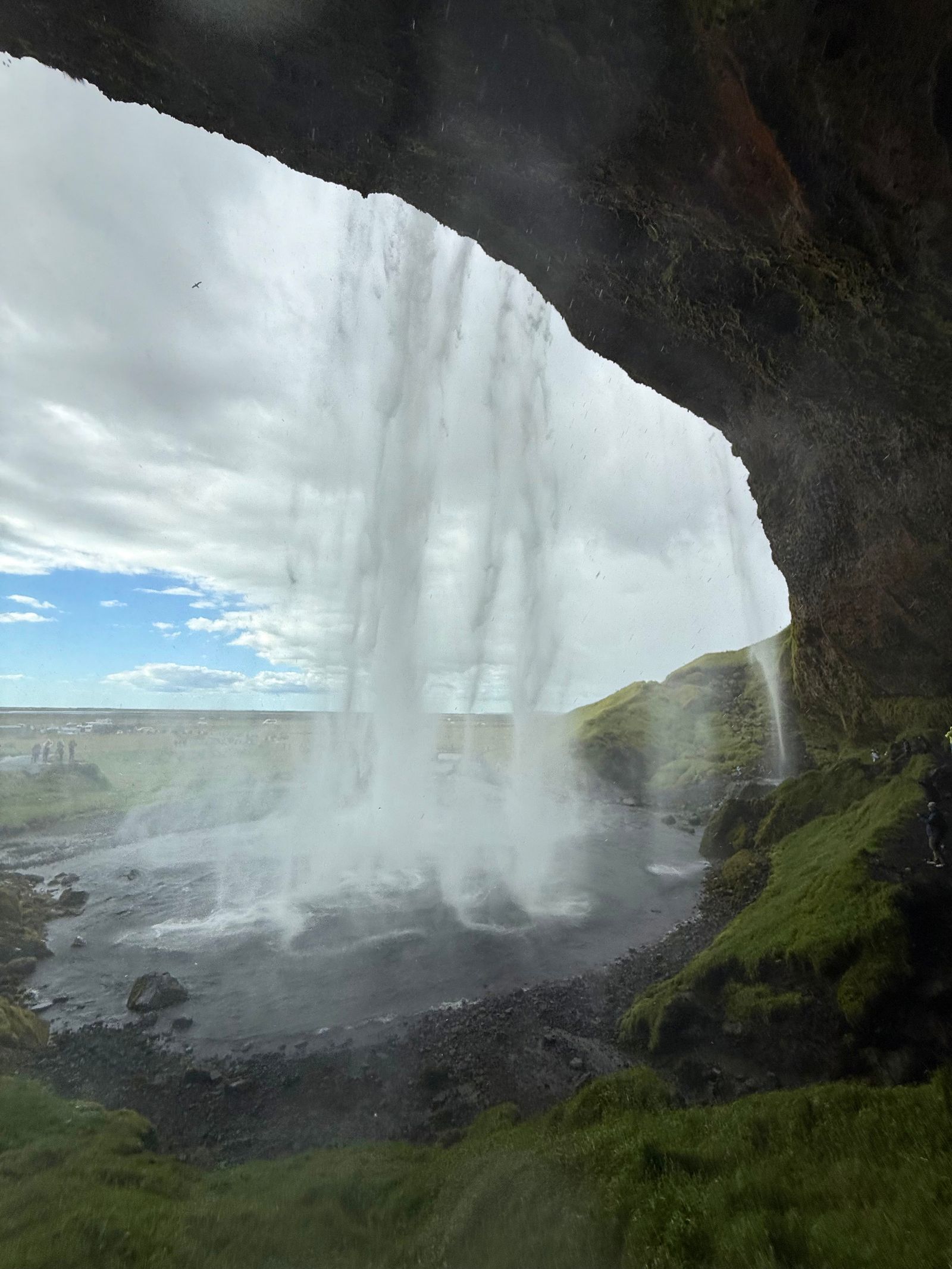 Waterfall falling past a rocky overhang into a misty pool, Skogafoss