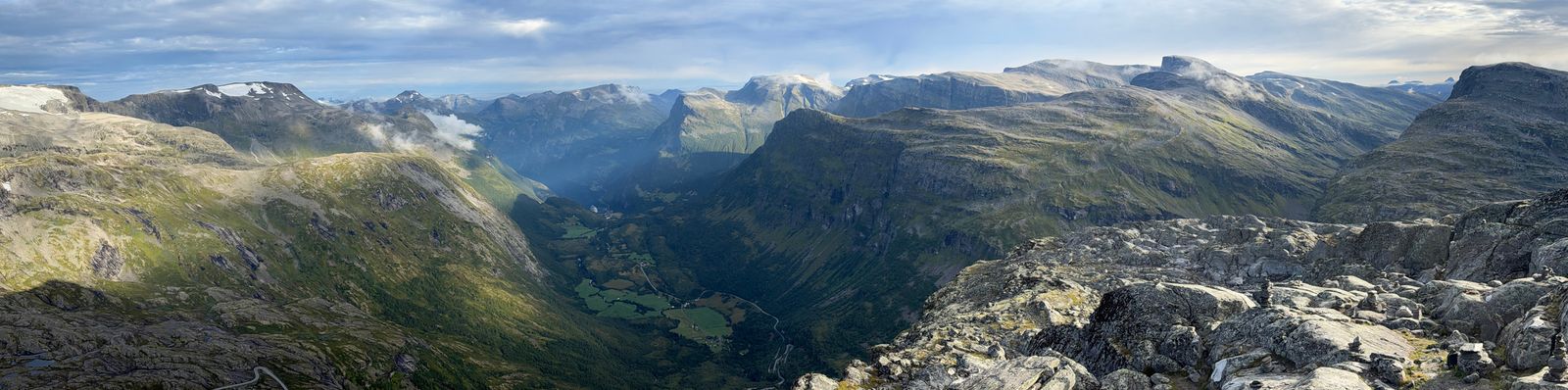 Mountain valley with fields and winding roads beyond rocky ridges, Geiranger