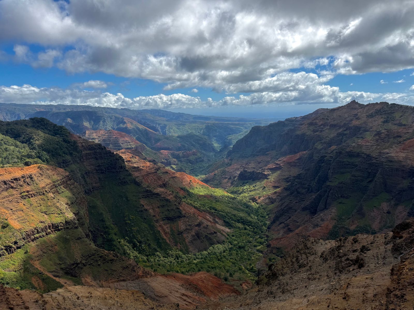 Layered canyon cliffs above a green valley under gray clouds, Napali Coast